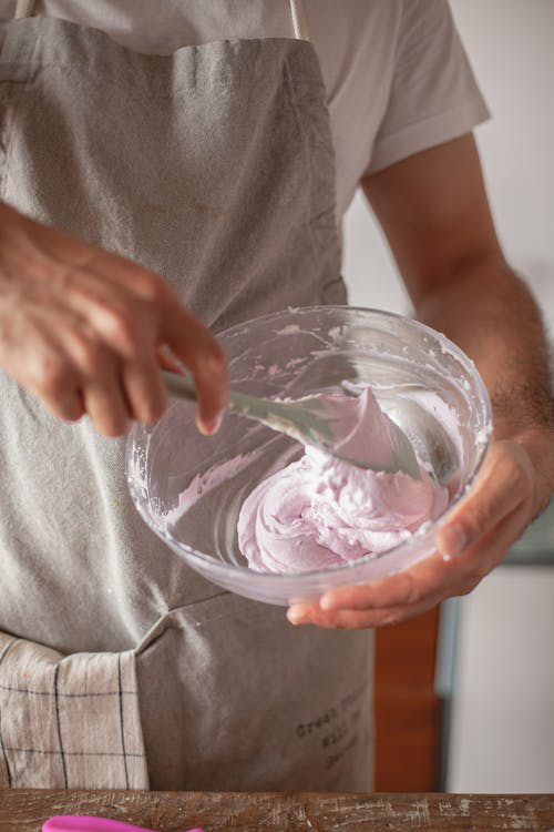 A person mixing whipped cream with a silicone spatula. 